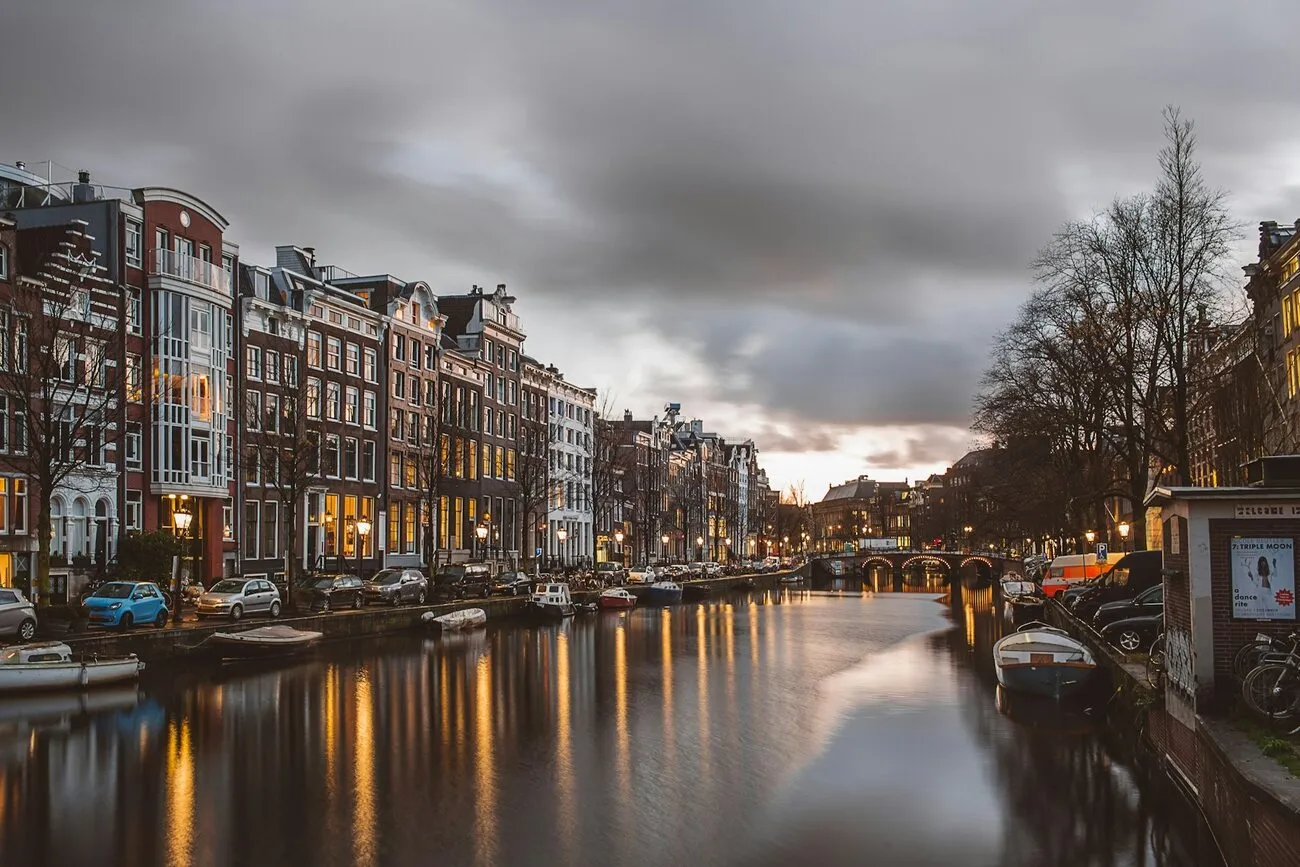 Canal din Amsterdam la lăsarea serii, cu case înalte din cărămidă